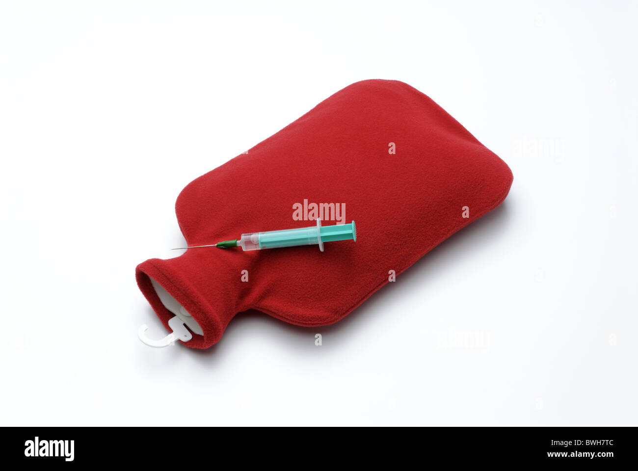 Wärmflasche mit rotem Einband und Injektionsspritzen Stockfoto