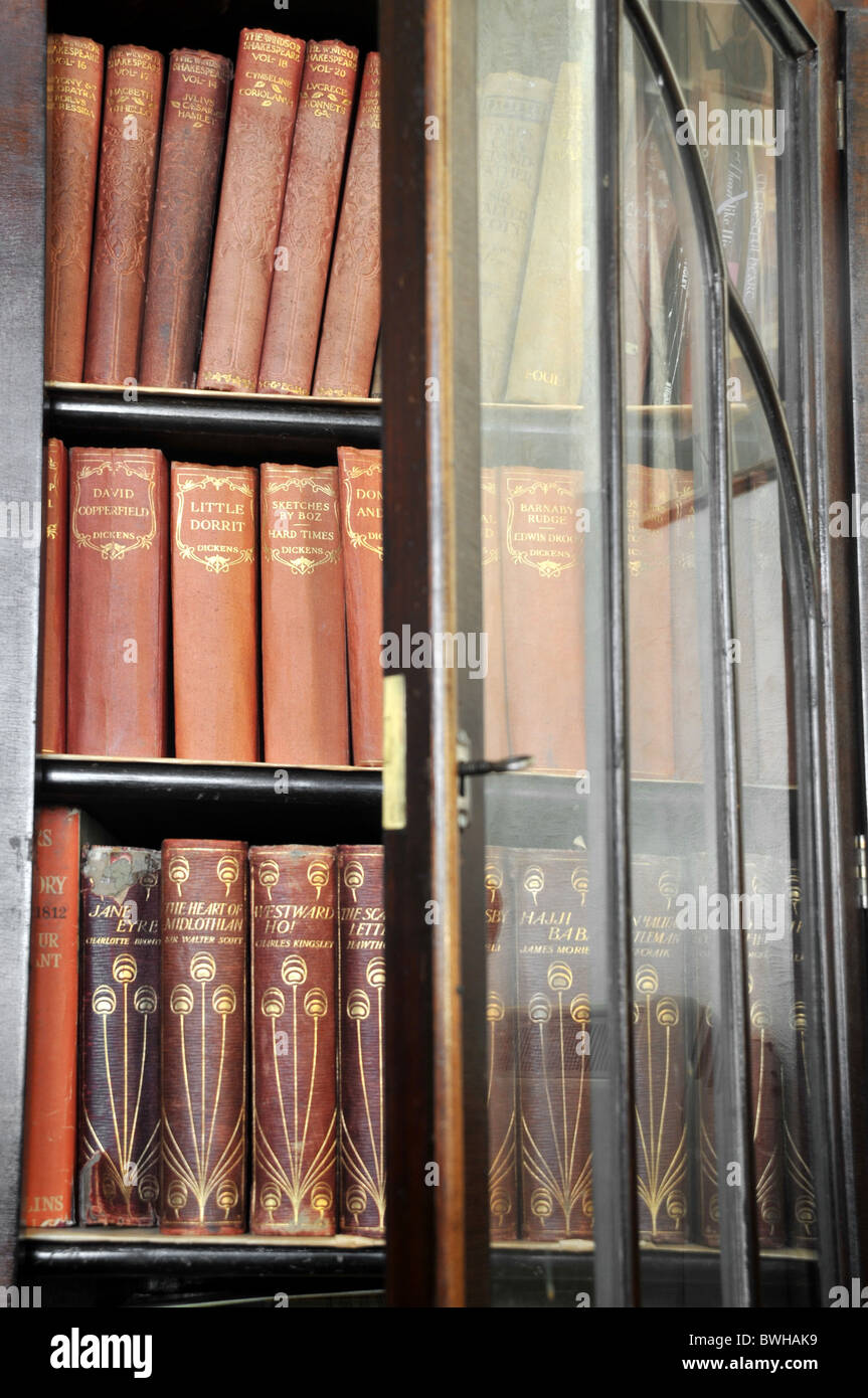 Eine geöffnete verglasten Tür Bücherregal mit alten Ausgaben der klassischen Romane. Stockfoto