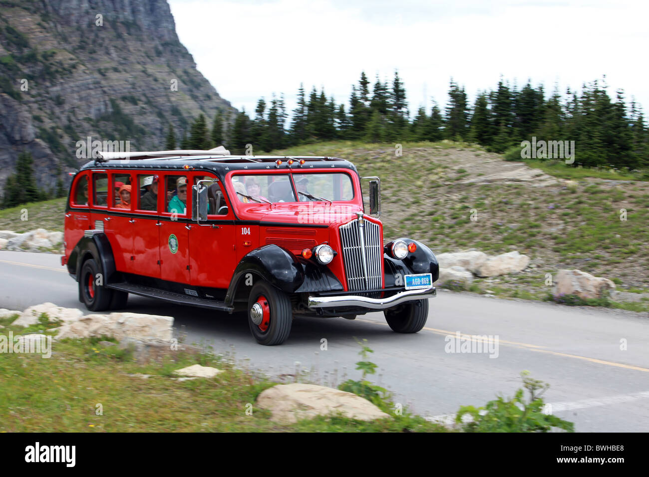 Rote Tour-Bus mit Menschen in Fahrt im Glacier National Park, Montana Stockfoto