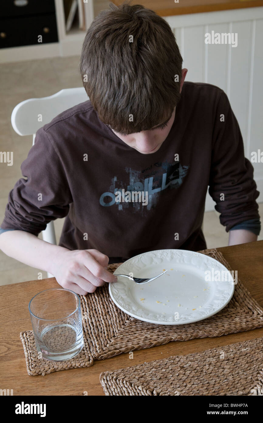 Teenager beendet seine Mahlzeit auf dem Tisch. Stockfoto