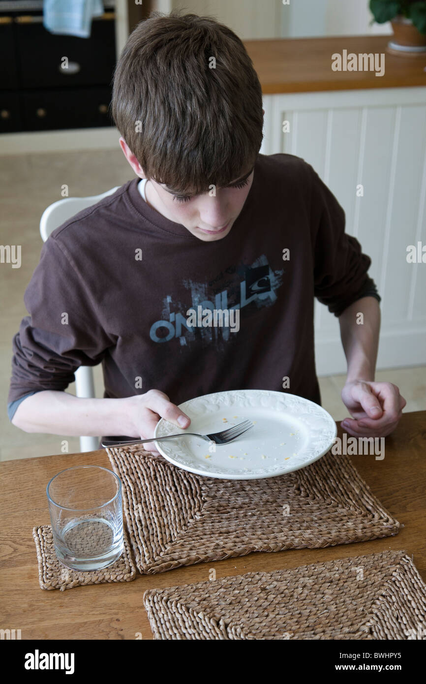 Teenager beendet seine Mahlzeit auf dem Tisch. Stockfoto
