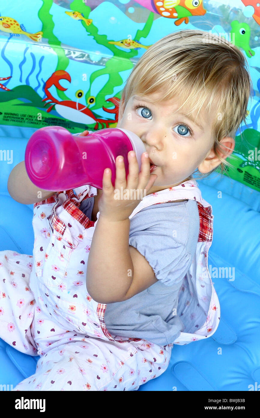 14 Monate altes Baby Mädchen mit blonden Haaren, Getränke aus der Flasche. Model-Release verfügbar Stockfoto