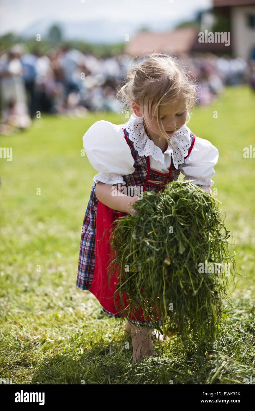 Mädchen (4-6 Jahre) trägt Dirndl mit Grass, möglicherweise ausgeführt, Antdorf, Oberbayern, Deutschland Stockfoto