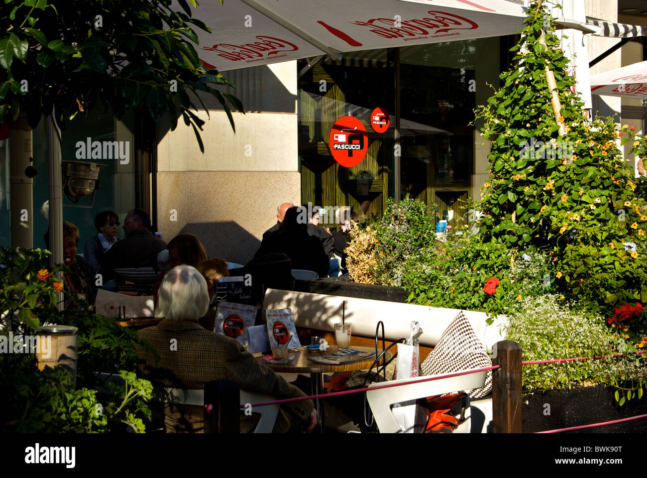 Gäste unter Sonnenschirmen im Café im freien Bürgersteig Patio in Leipzig Altstadt Stockfoto