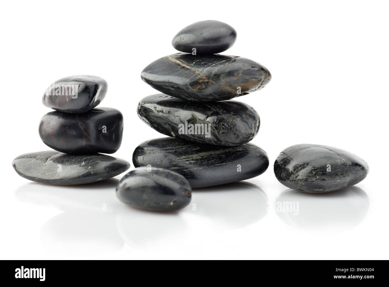 Schwarze Natursteine in Pyramide über weiß Stockfoto