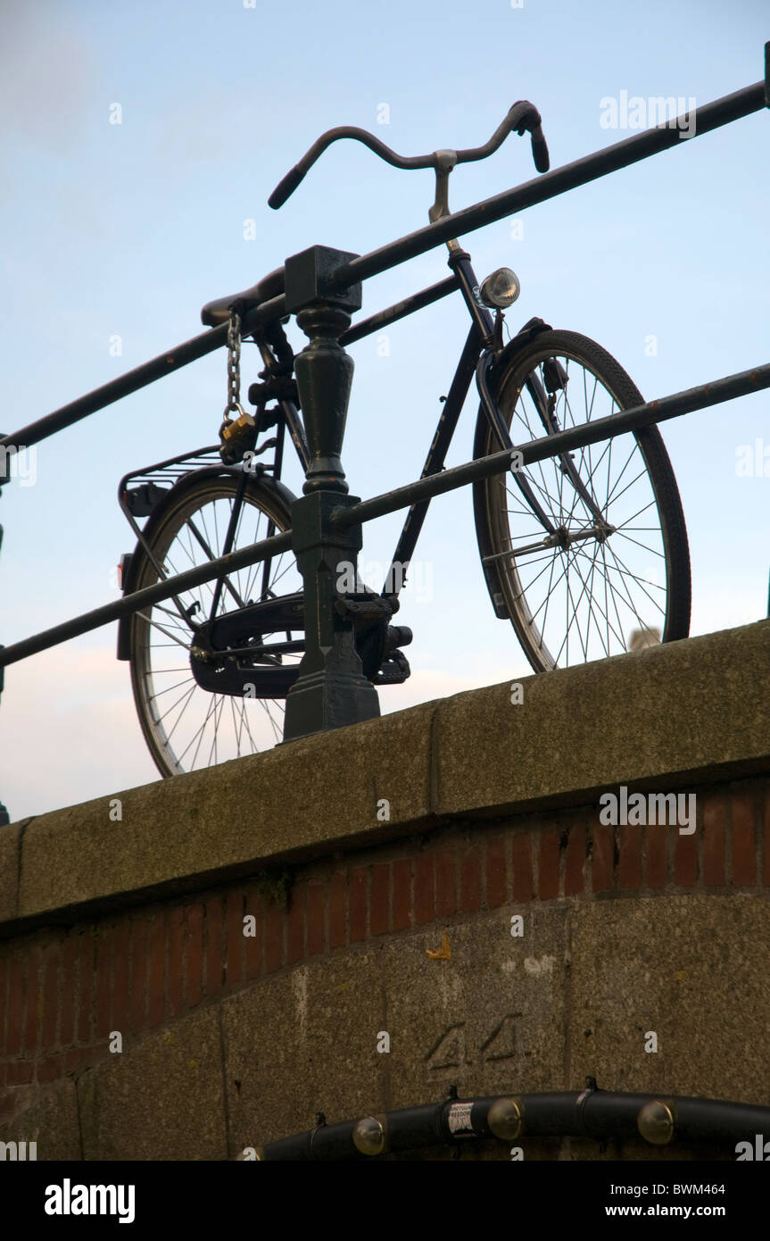 ein Fahrrad gesperrt, um das Geländer einer Brücke in Amsterdam Stockfoto