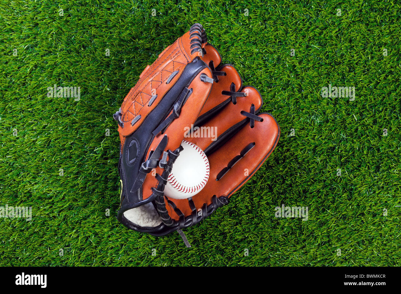 Foto eines Baseball-Handschuhs und Kugel auf dem Rasen. Stockfoto