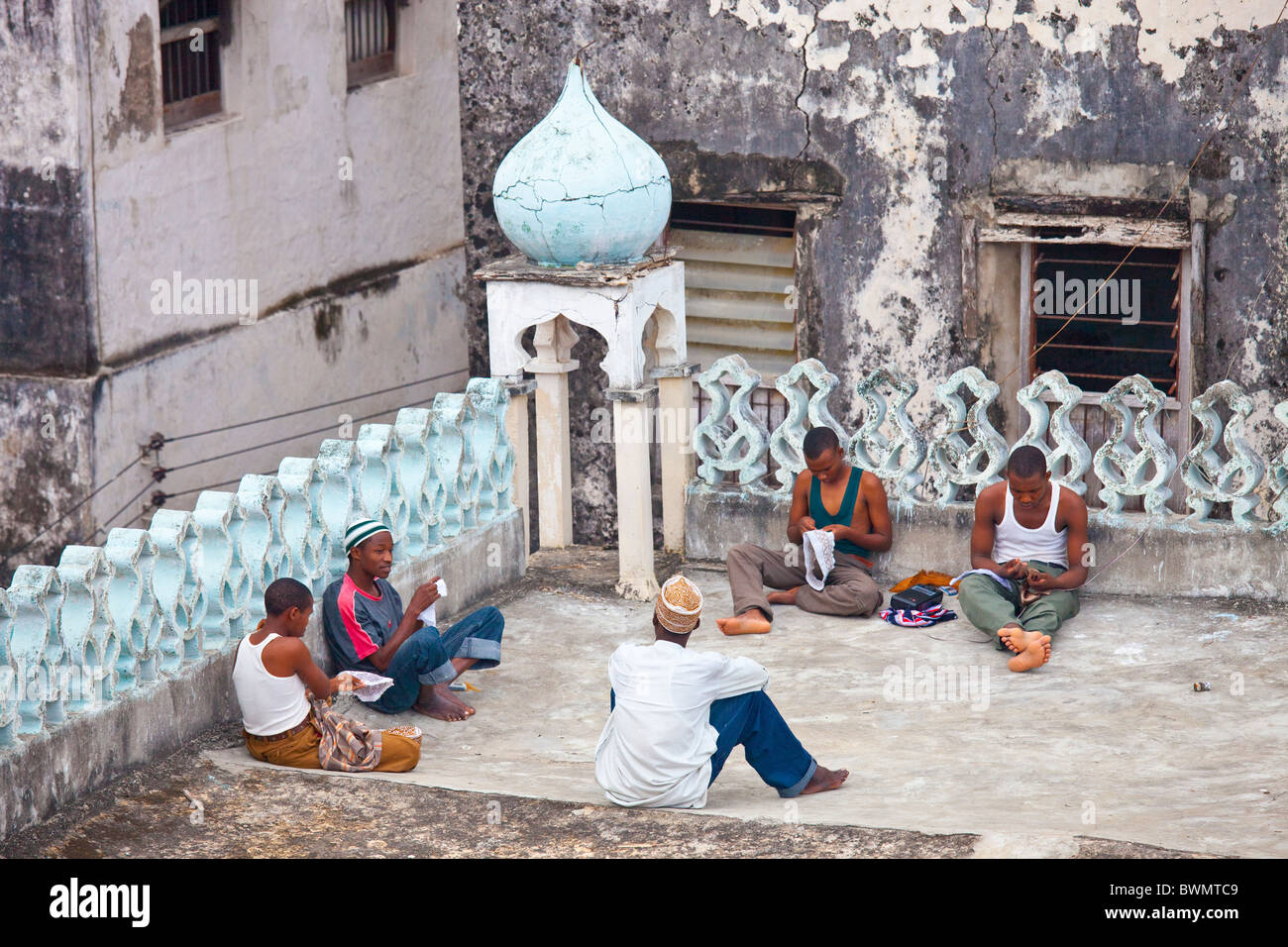 Junge Männer machen Hüte auf dem Dach der Moschee, Insel Lamu, Kenia Stockfoto