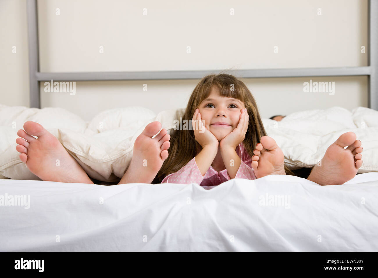 USA, Illinois, Metamora, Mädchen (6-7) auf Bett in der Nähe der Eltern Füßen liegend Stockfoto