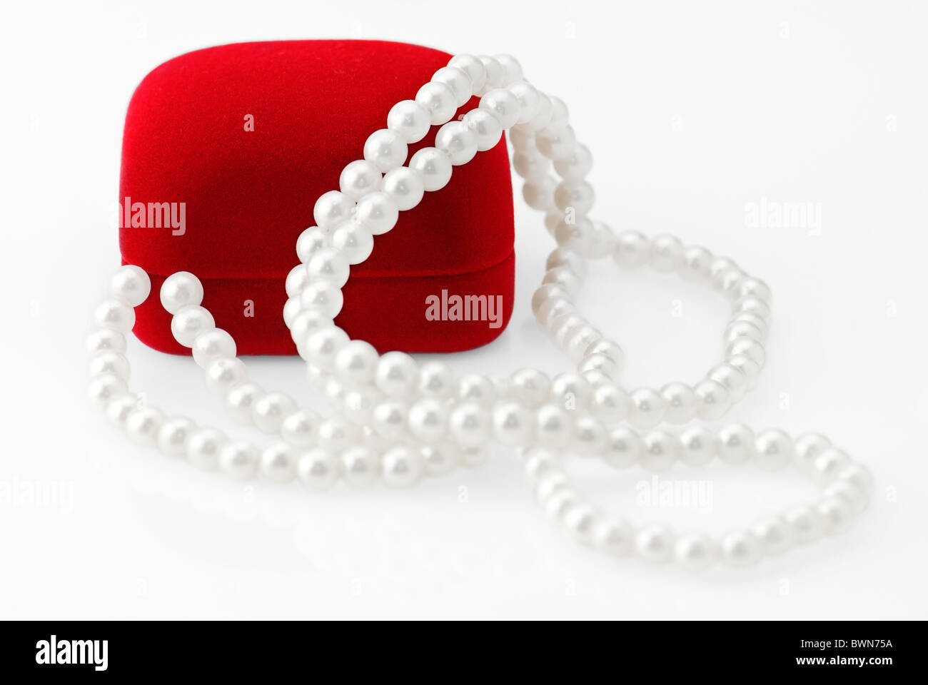 Roter samt-Geschenk-Box und Perlenkette über weiß. Geringe Schärfentiefe Stockfoto