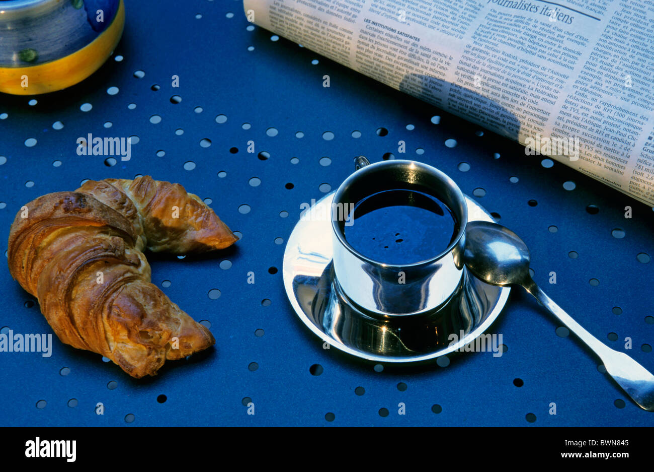 Croissant und Kaffee Tasse auf dem Tisch mit der Morgenzeitung, Frankreich. Stockfoto