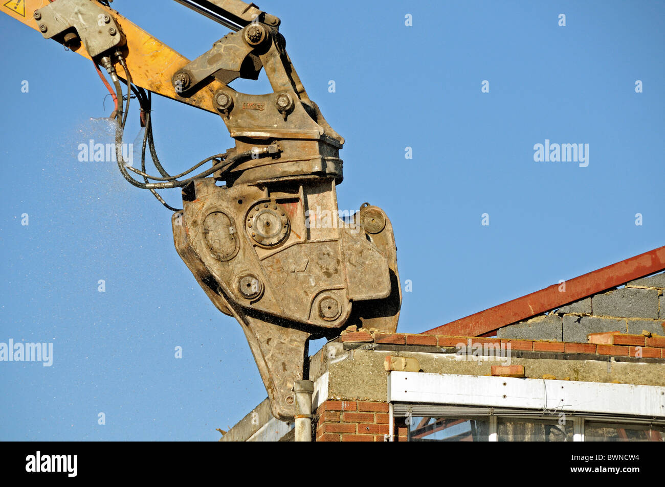 Nahaufnahme von Pulverisierer, ein Abriss-Werkzeug auf dem Arm eines Baggers Abriss eines Gebäudes gegen Himmel Stockfoto