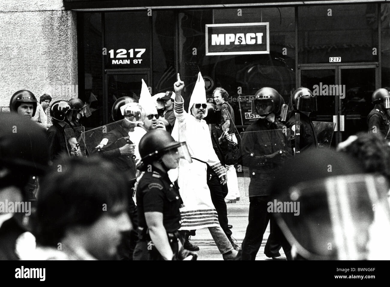 Dallas Texas Polizei in Riot gear für KKK Protest. KKK Person hält Hand. Stockfoto