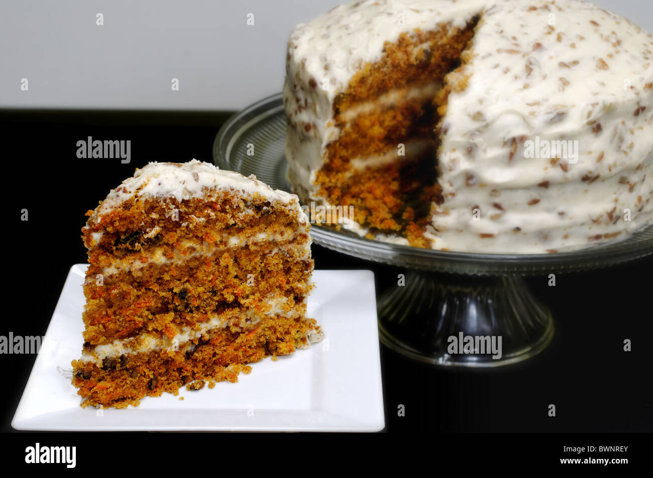 Stück Karottenkuchen mit ganzen Kuchen im Hintergrund. Stockfoto