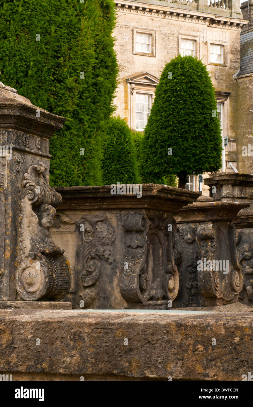 Str. Marys Kirchhof mit Eiben und Cotswold Steingebäude im Hintergrund, Painswick, Gloucestershire, UK Stockfoto
