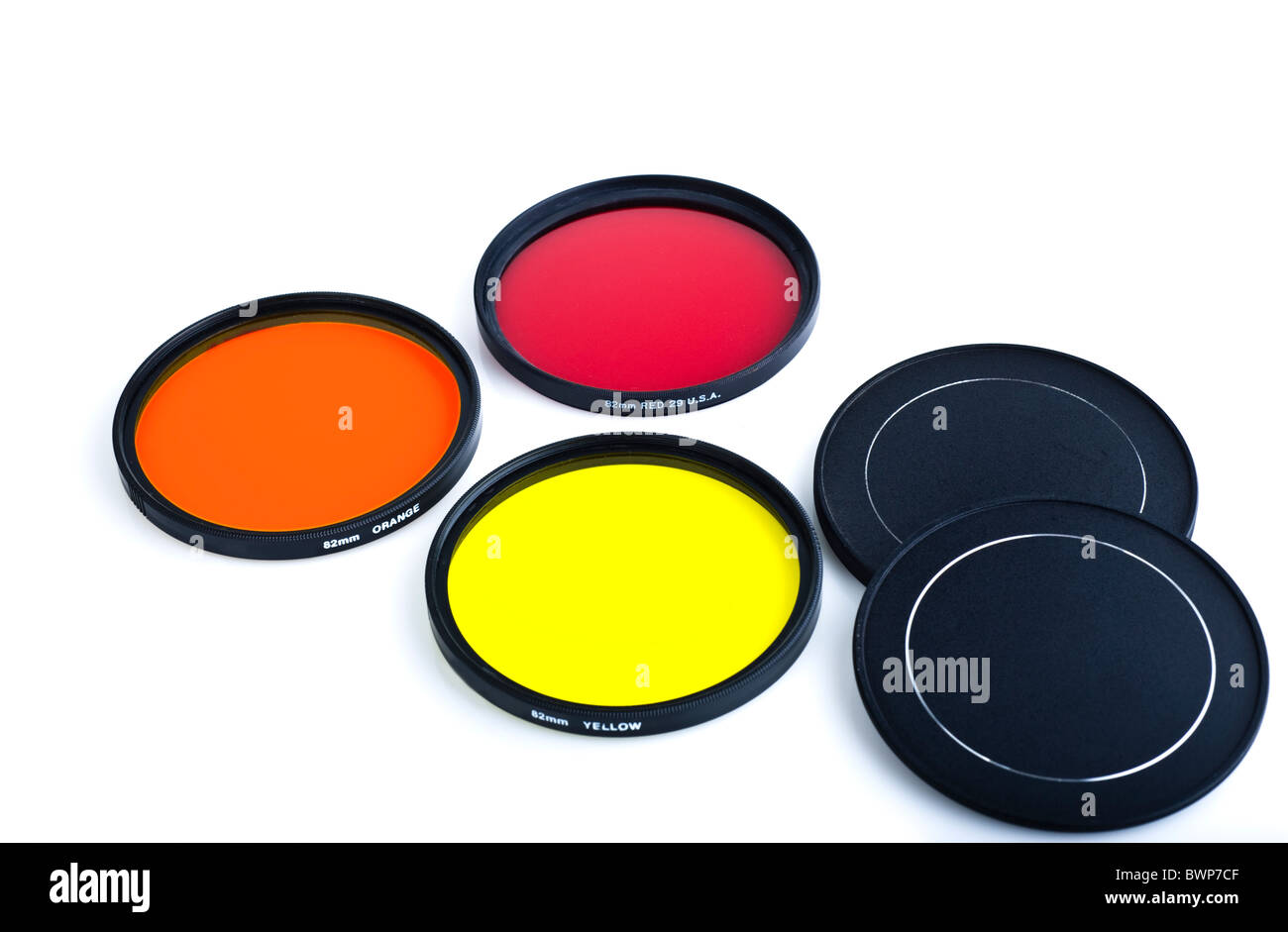 Rote, gelbe und orange Objektiv-Filter für Filmkameras auf weißem Hintergrund. Stockfoto