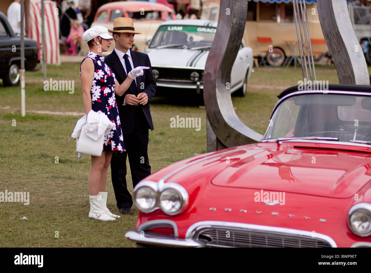 Paar in Tracht, die Inspektion einer klassischen roten Corvette bei Vintage beim Goodwood festival Stockfoto