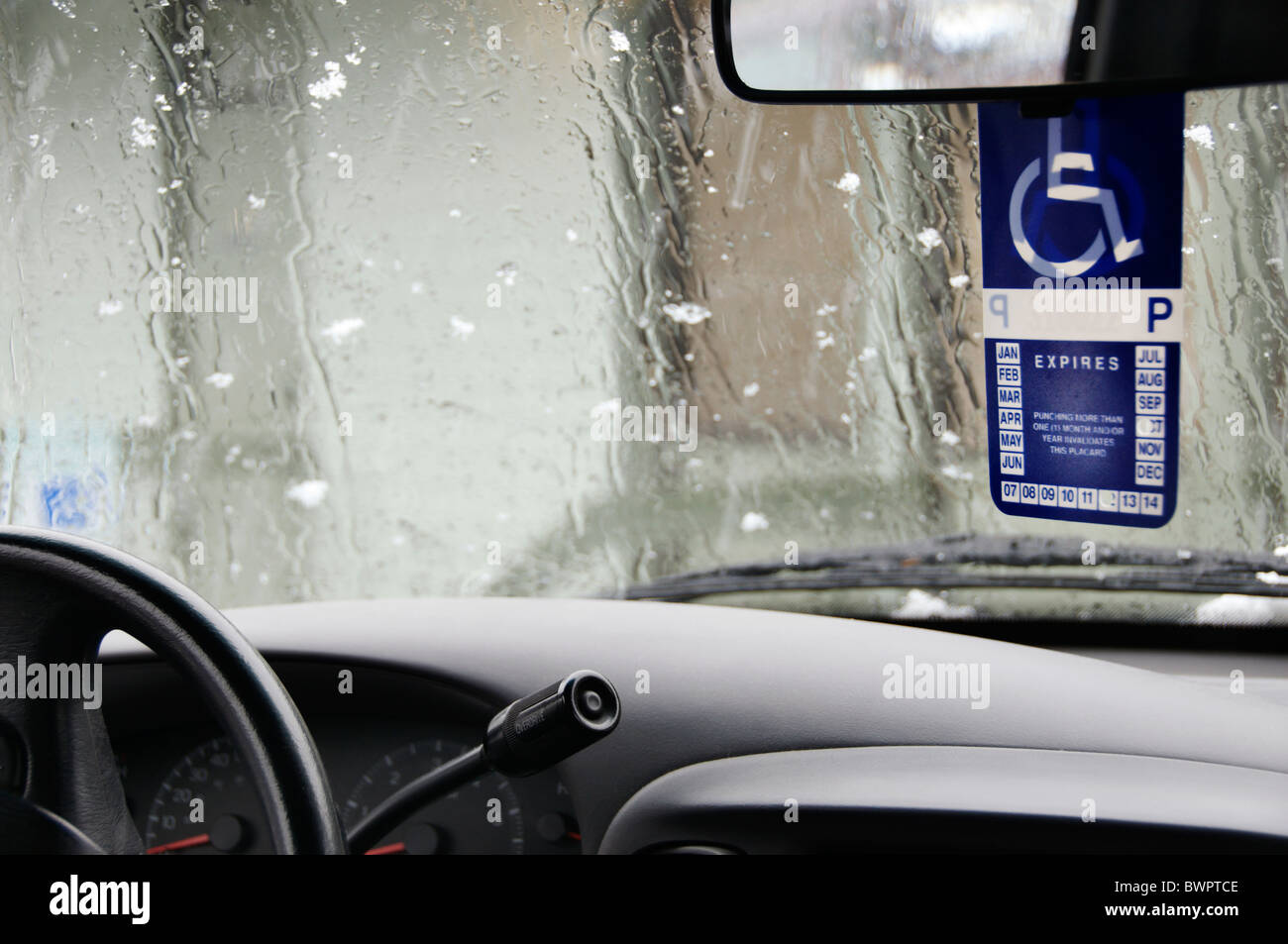 Einem behinderten Plakat hängt von den Rückspiegel ein Fahrzeug geparkt an einem verschneiten Regentag in Olympia, Washington. Stockfoto