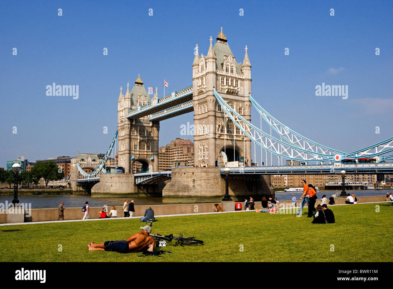 UK London Tower Bridge Wahrzeichen Thames River Shore am Flussufer Menschen Fußgänger Vereinigtes Königreich England Stockfoto