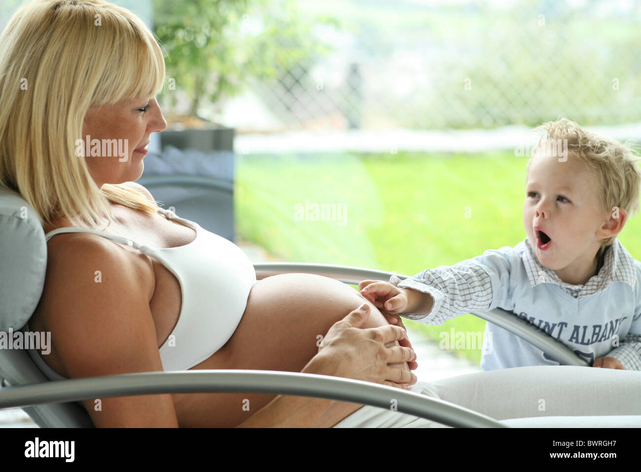 Indoor innen Frau schwanger Schwangerschaft sitzen Stuhl entspannt entspannten Bauch oben blond Mutter Geburt baby Stockfoto
