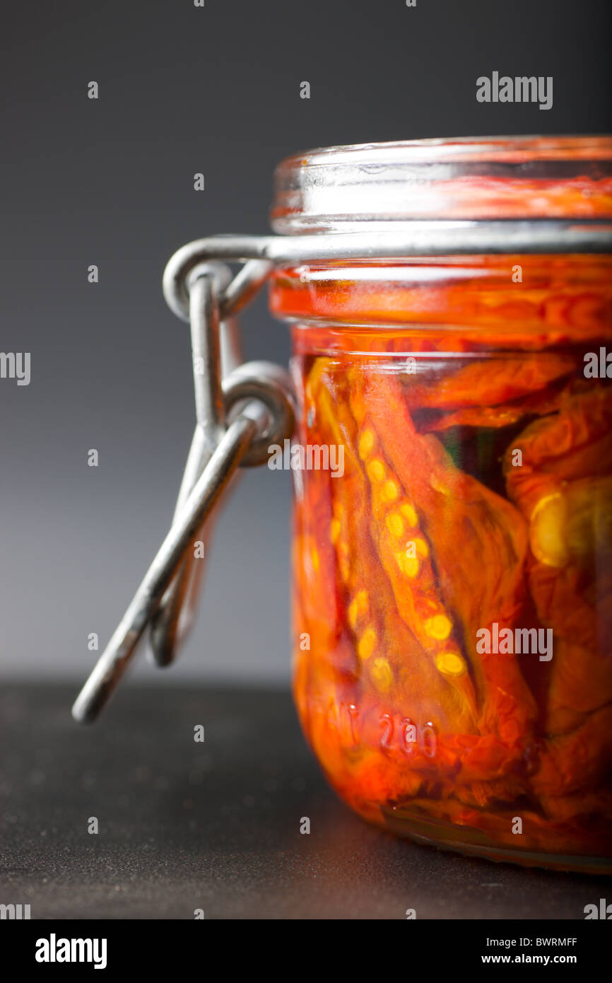 Ein Glas gefüllt mit Sun-Dried Tomaten und Olivenöl auf einem schwarzen Hintergrund. Stockfoto