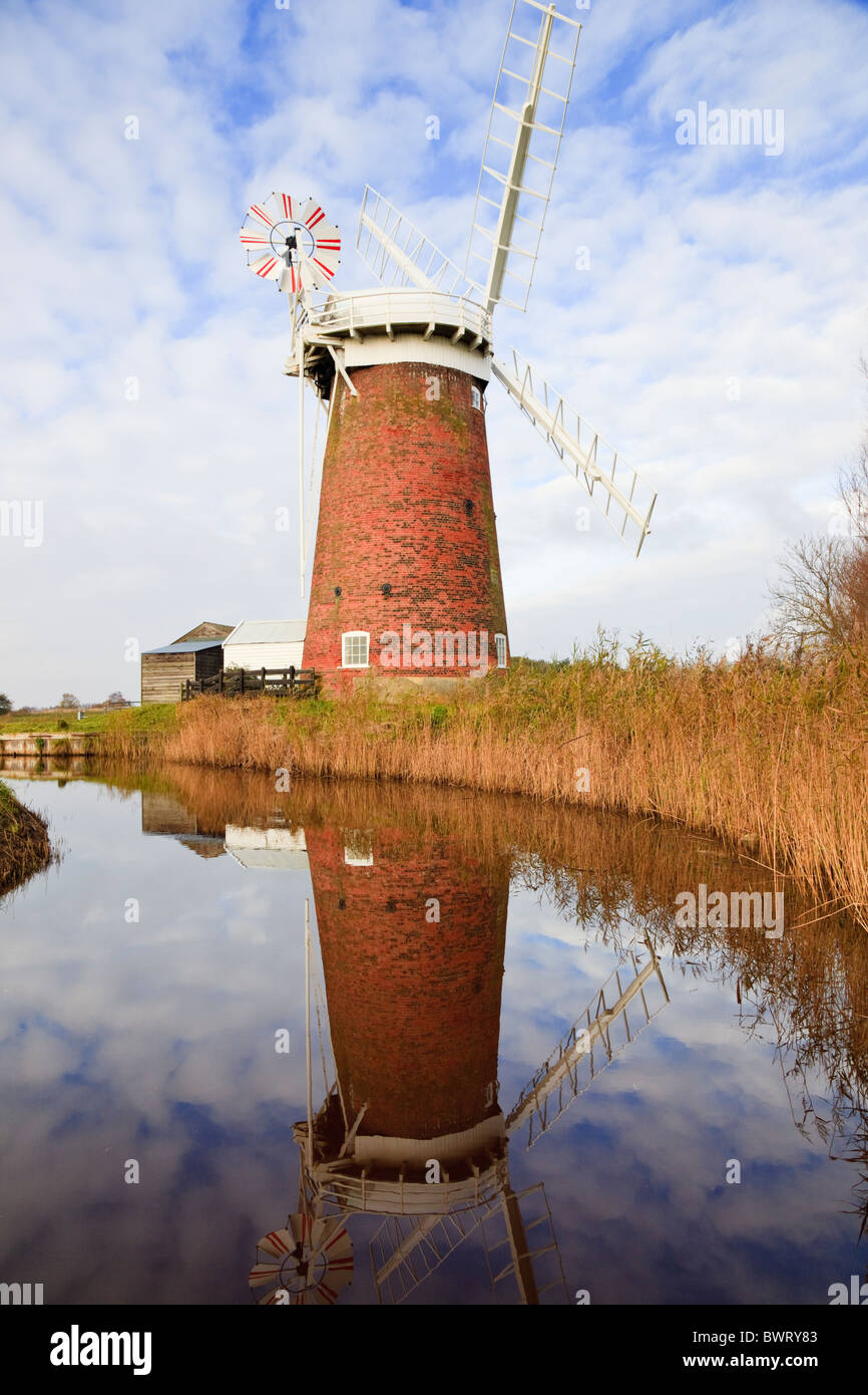 Horsey Windmühle Windpumpe spiegelt sich in einem Deich Wasserlauf, gesäumt von Schilf in Norfolk Broads. Horsey Norfolk England UK Großbritannien Stockfoto