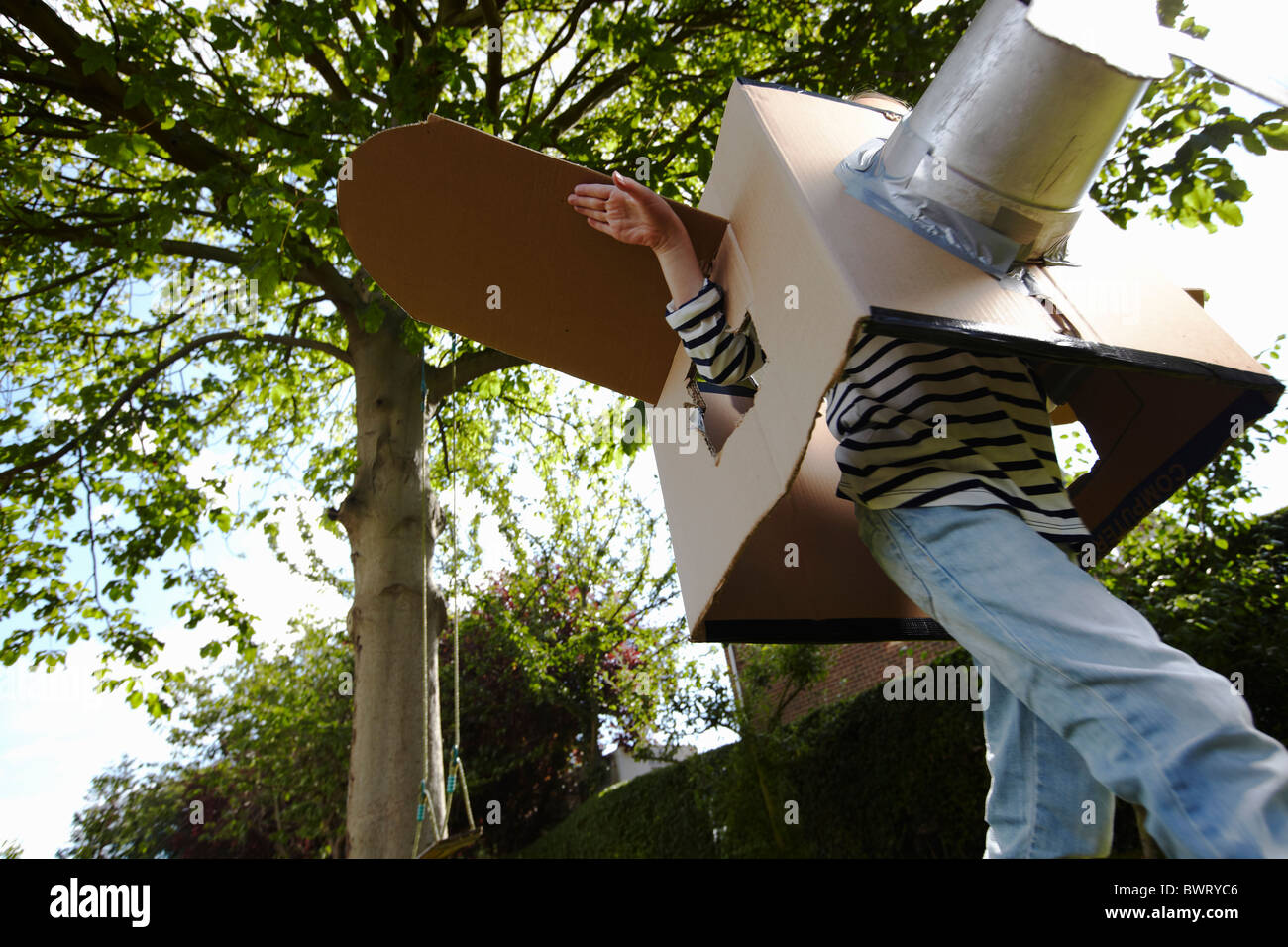 Junge Mädchen spielt mit Pappe, die Flugzeug in Land Garten Stockfoto