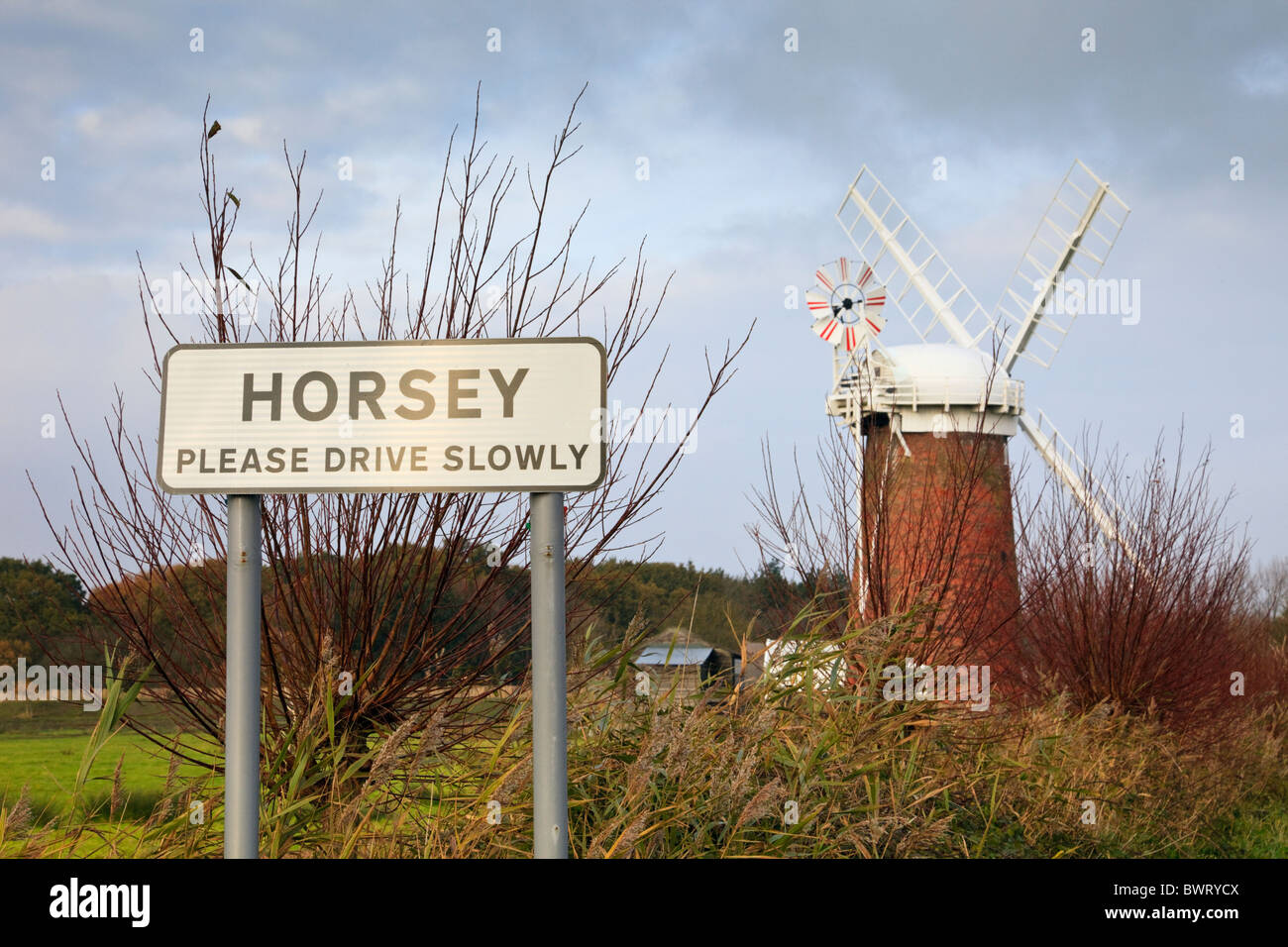 Horsey, Norfolk, England, UK, Europa. Ortsschild mit der Windmühle Windpumpe in den Norfolk Broads Stockfoto