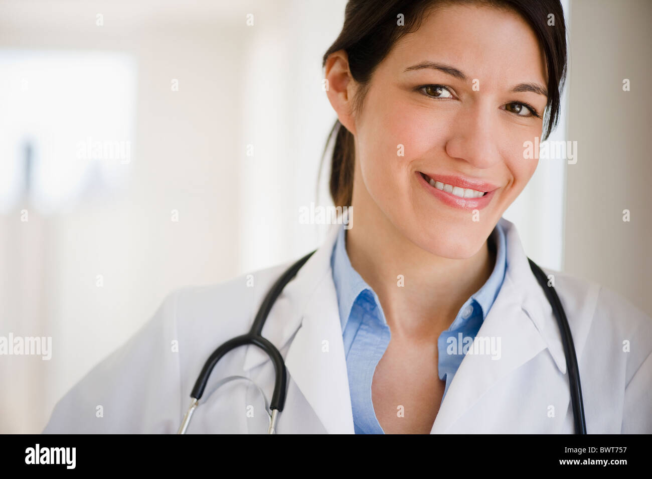 Lächelnd Mischlinge Arzt im Kittel mit Stethoskop Stockfoto
