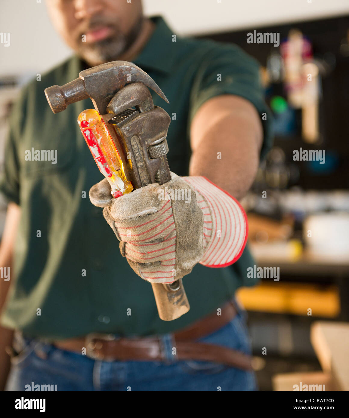 African American Zimmermann holding, Schraubendreher, Schraubenschlüssel und hammer Stockfoto