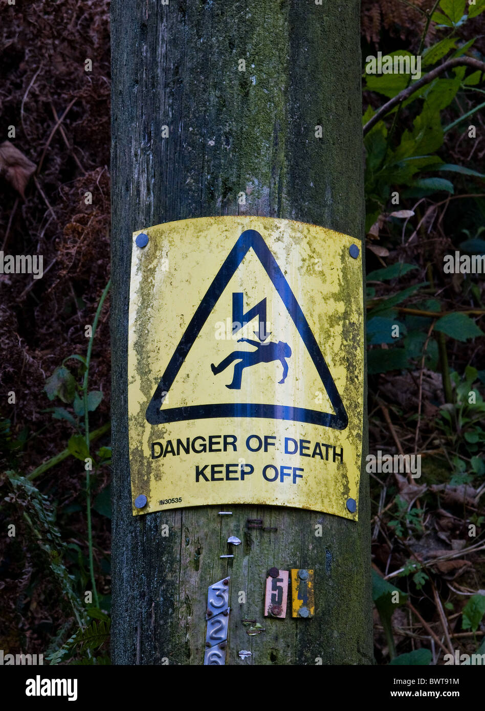 Ein metall Warning sign zu einem hölzernen Pfosten genagelt. Foto von Gordon Scammell Stockfoto