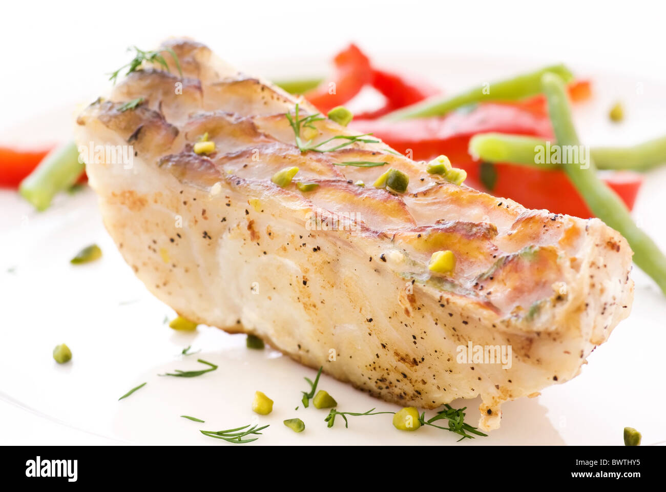 Papagei-Fisch-Steak mit Gemüse als Closeup auf einem weißen Teller Stockfoto