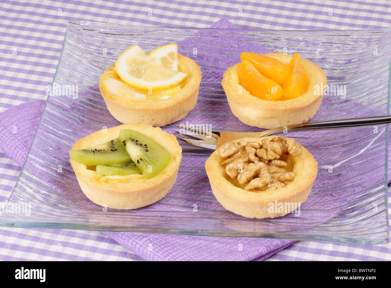 Nahaufnahme von einigen Mini-Obstkuchen serviert auf einer Glasplatte mit Dessertgabel. Selektiven Fokus. Stockfoto