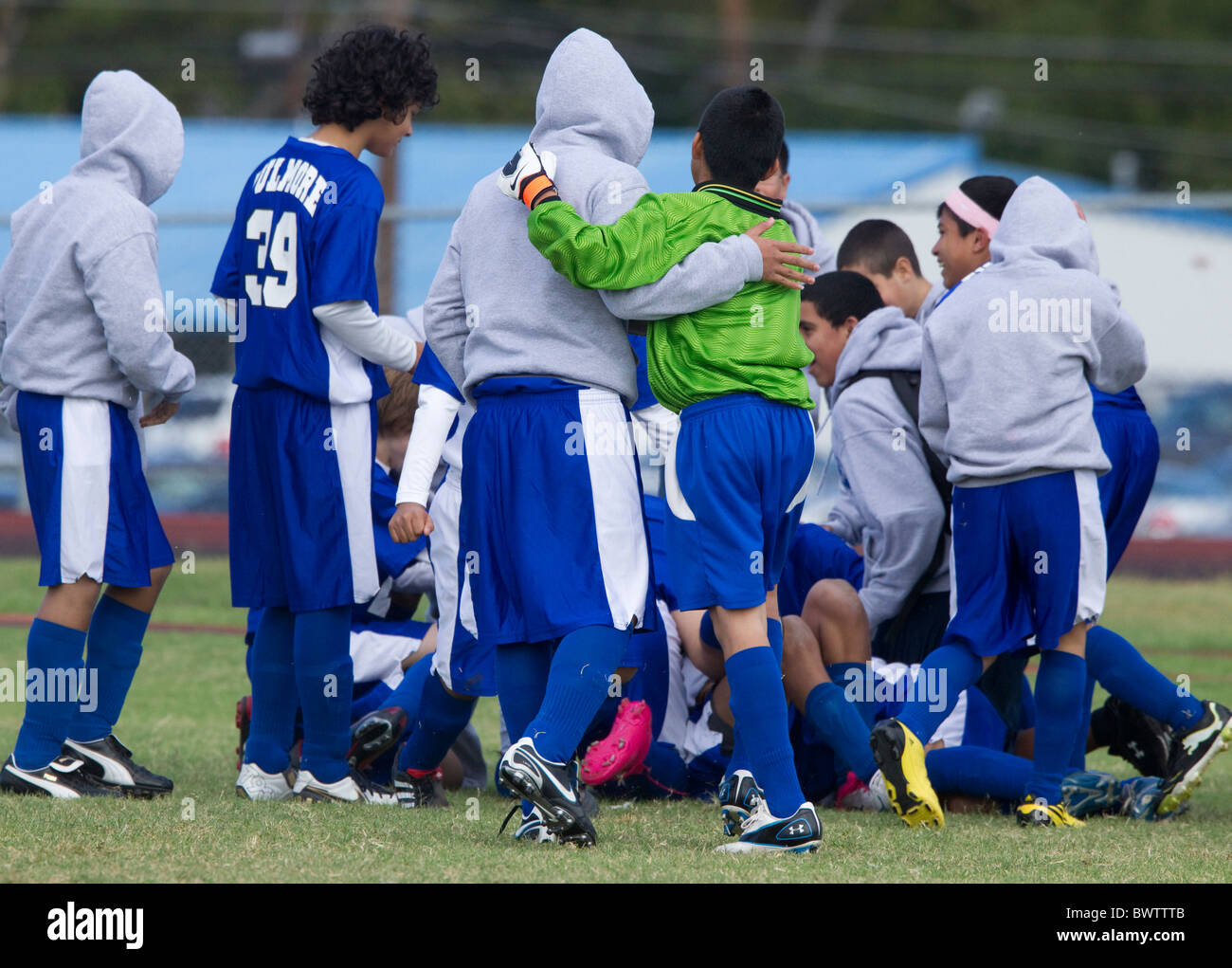 Mittelschule jungen Fußball-Team-Mitglieder drängen, um warm zu bleiben, während der Timeout des Spiels am kühlen Morgen in Austin, Texas Stockfoto