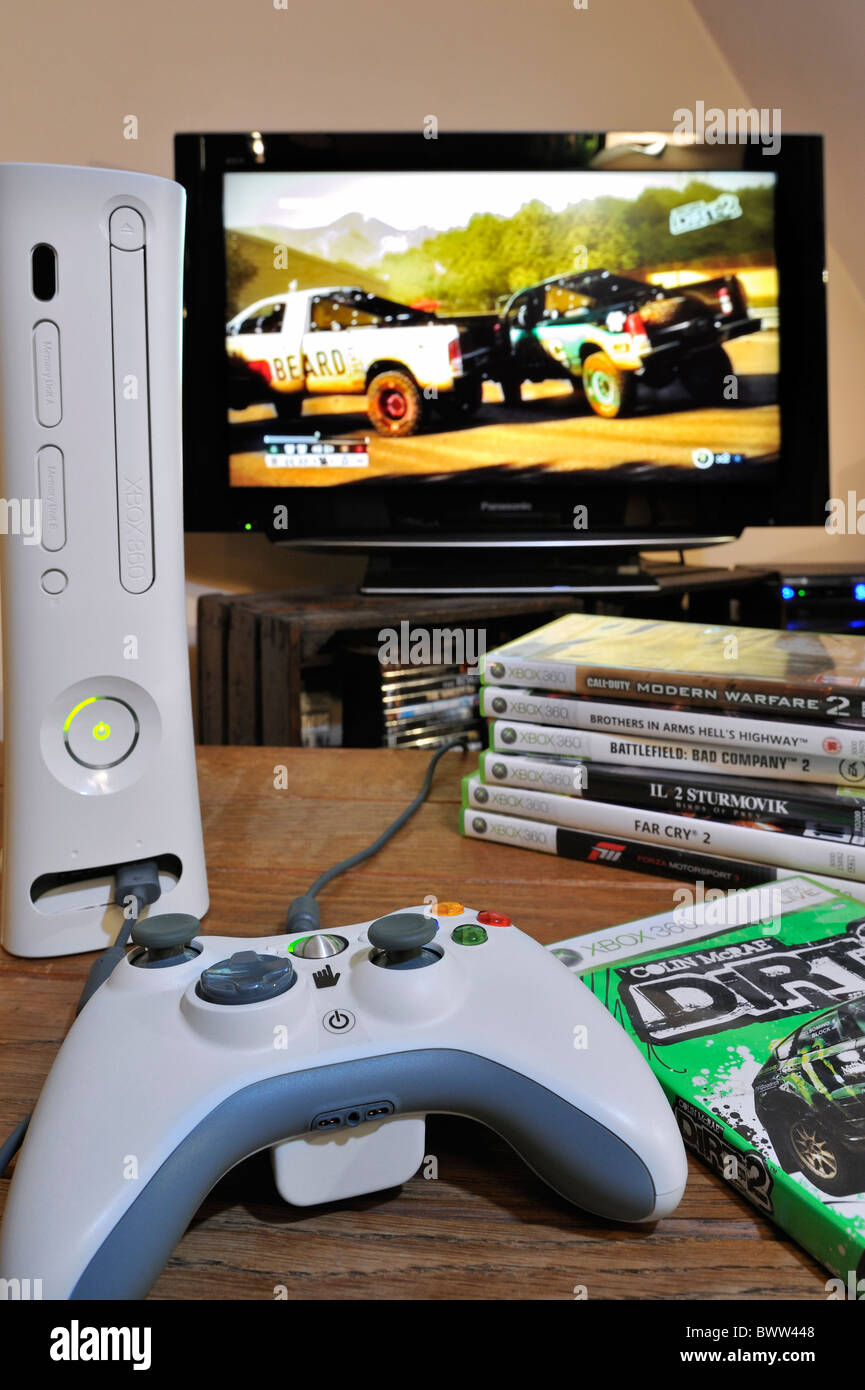 Konsole, Controller und Haufen von Videospielen vor TV-Bildschirm zeigt Autos im Rennspiel Stockfoto