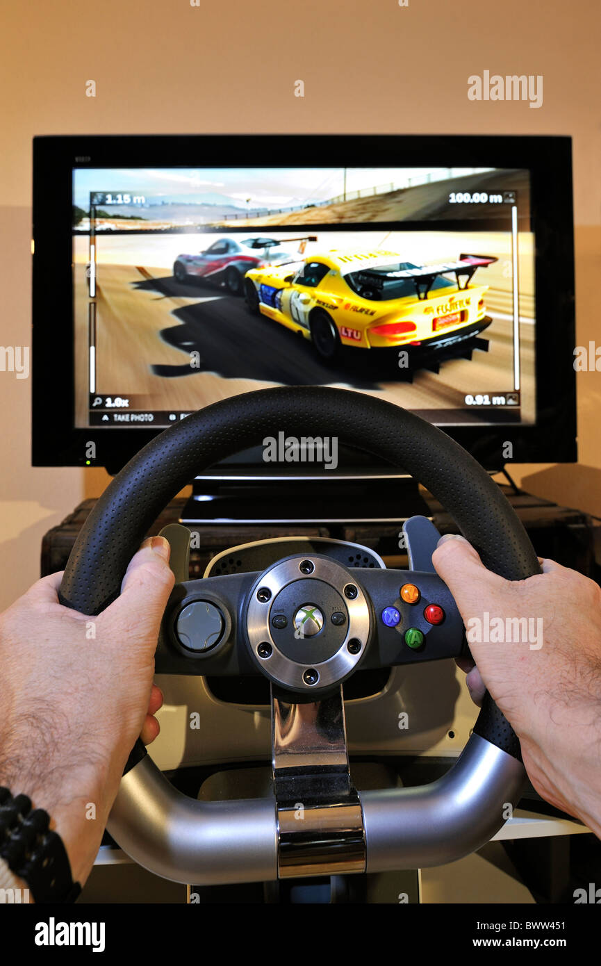 Lenkrad-Controller vor TV-Bildschirm zeigt Autos im Rennspiel Stockfoto