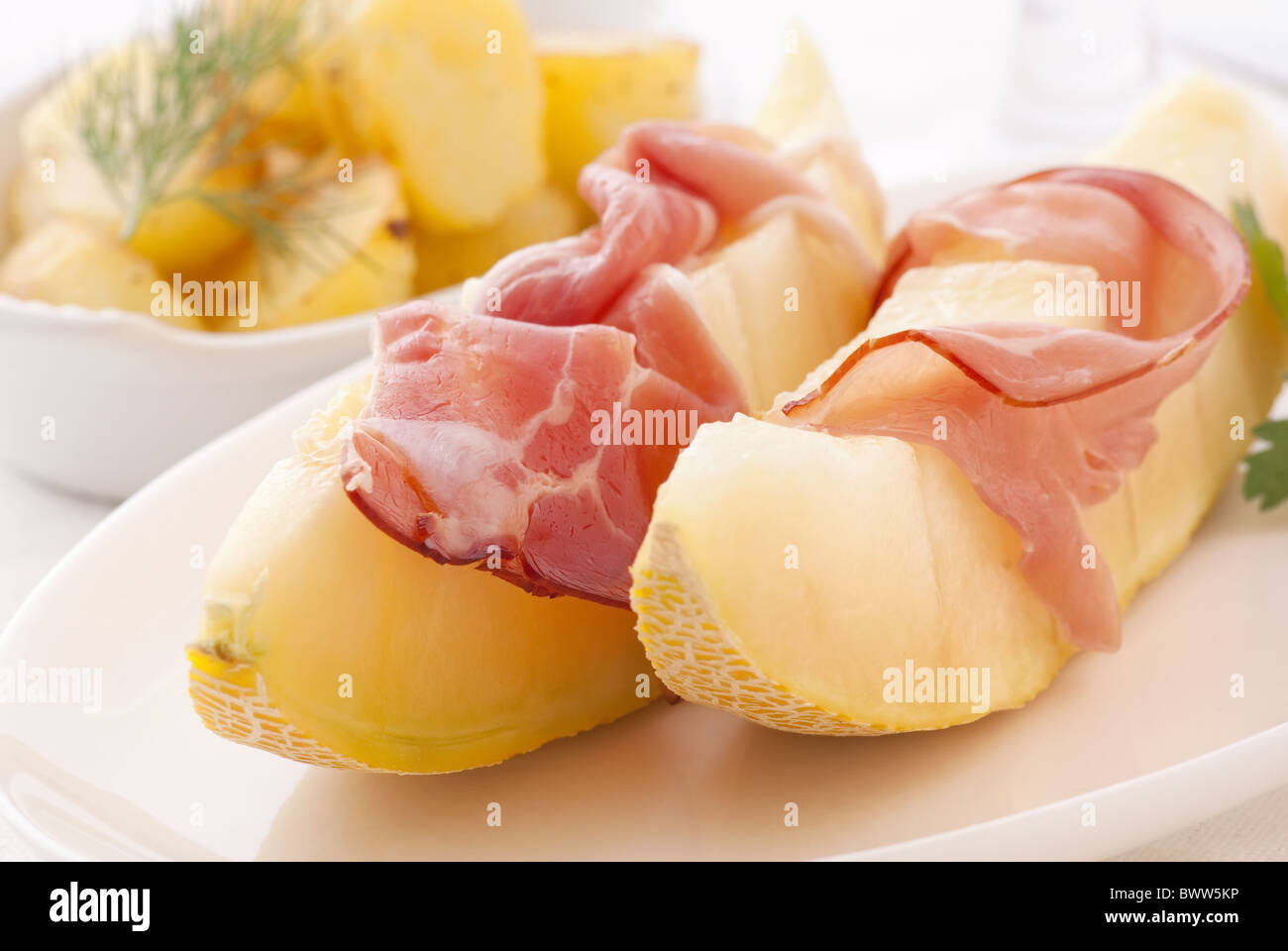 Rock-Melone mit Schinken und Kartoffeln als Closeup auf einem weißen Teller Stockfoto