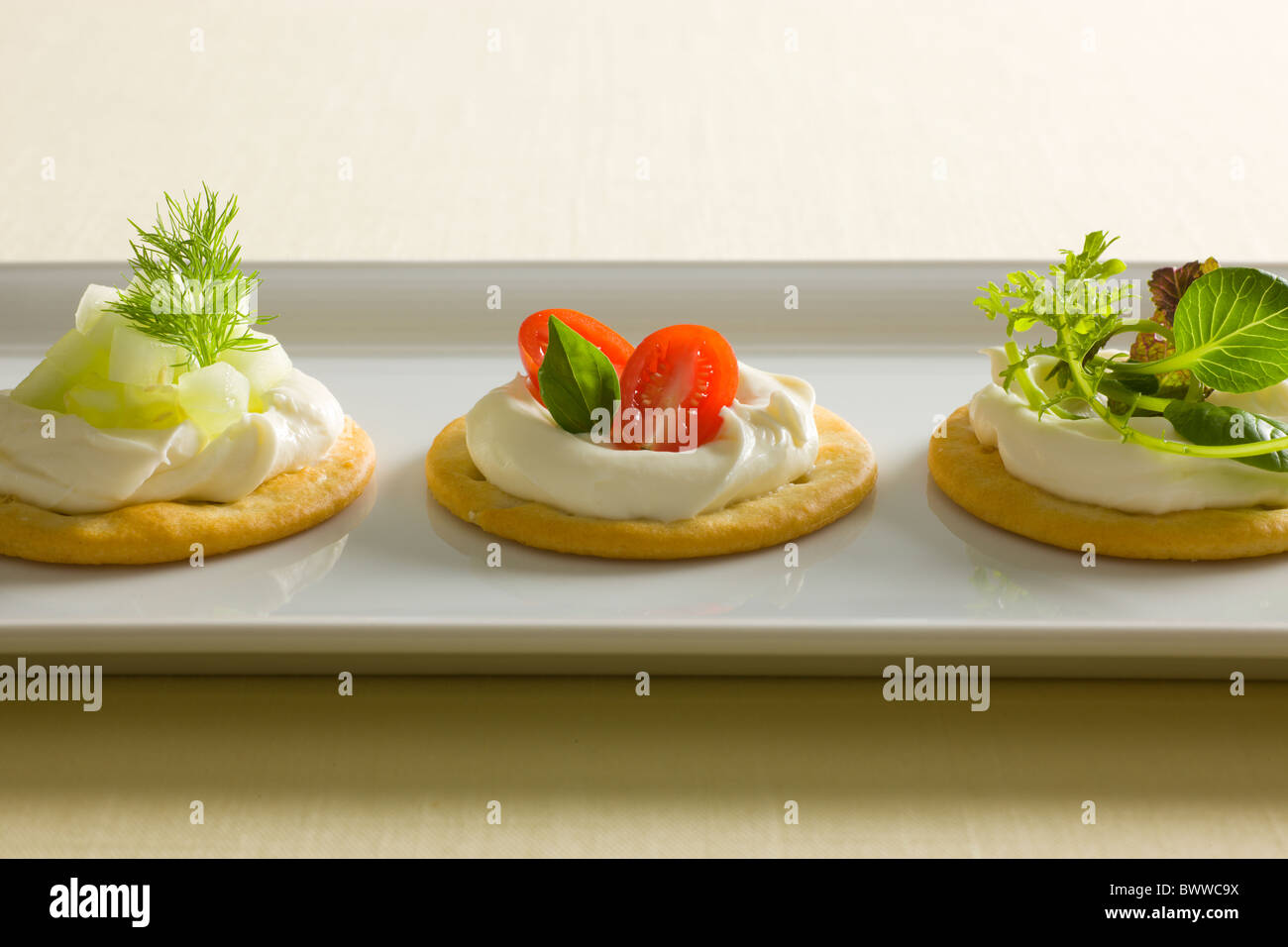 Kekse mit cremiger Käse verbreiten, garniert mit Tomaten, Basilikum, Gurken, Dill, gemischte grün und Radieschen oben auf einem weiß r Stockfoto