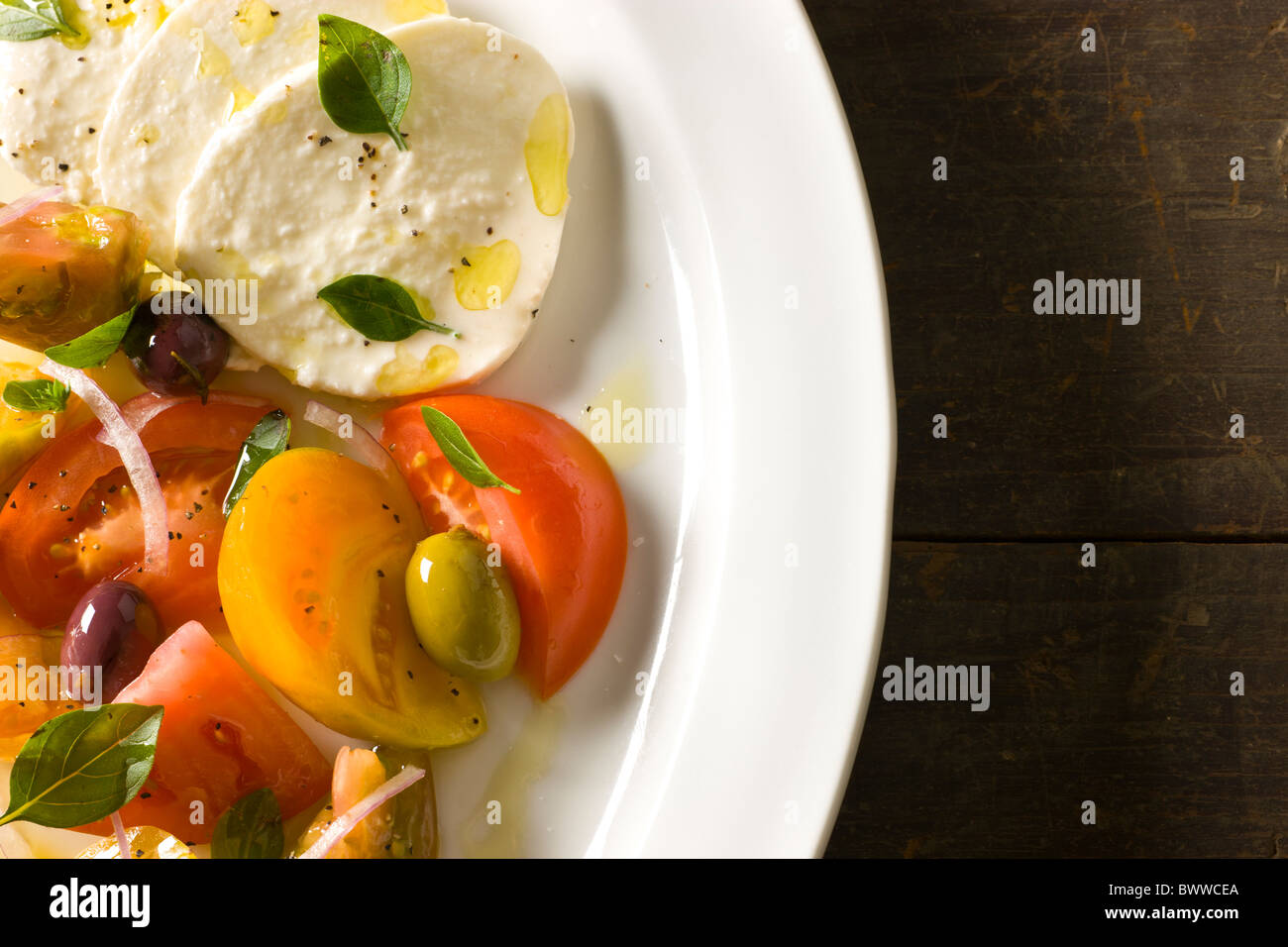 Mozzarella mit Tomaten und Oliven, Olivenöl und frischer Oregano Stockfoto