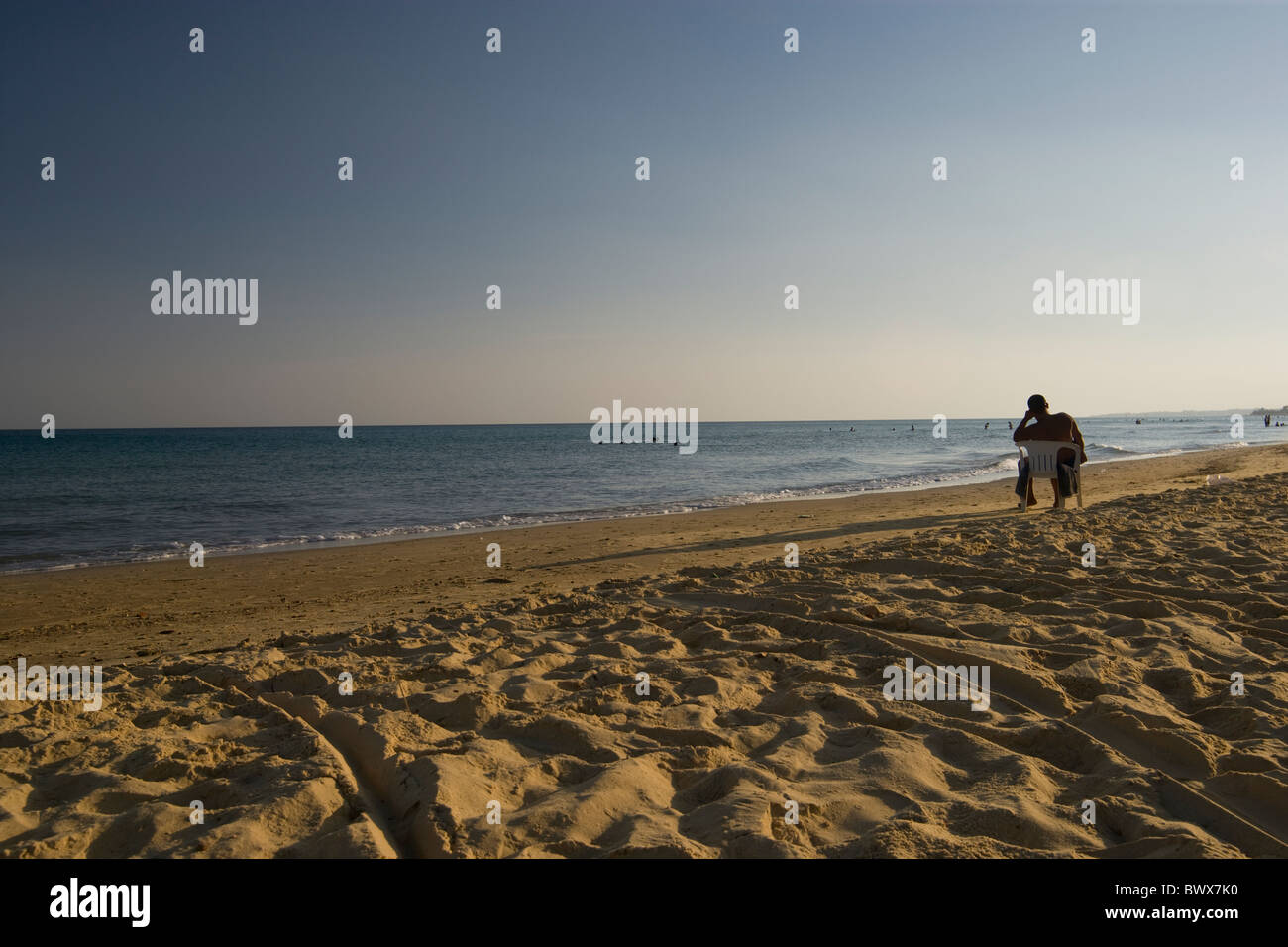 Mann sitzt auf Plastikstuhl Sonnenuntergang Strand Sommer Stockfoto