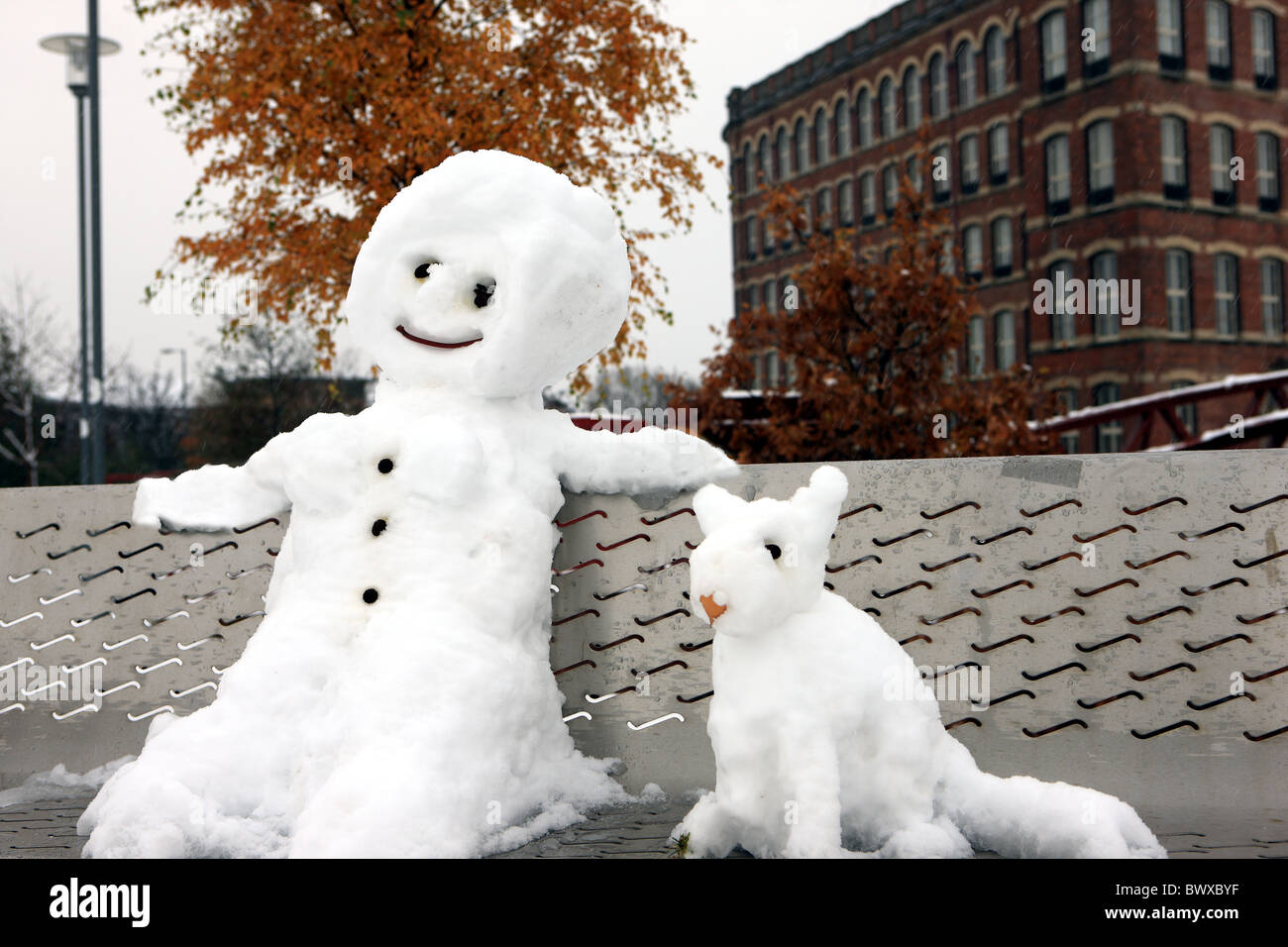 Schneemann und Hund sitzt auf einer Parkbank Stockfoto