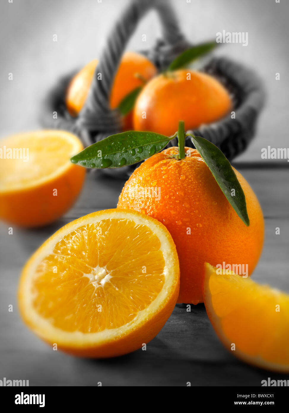 Frische Orangen ganze und geschnittene Hälften mit Blättern in einer Küche-Einstellung Stockfoto