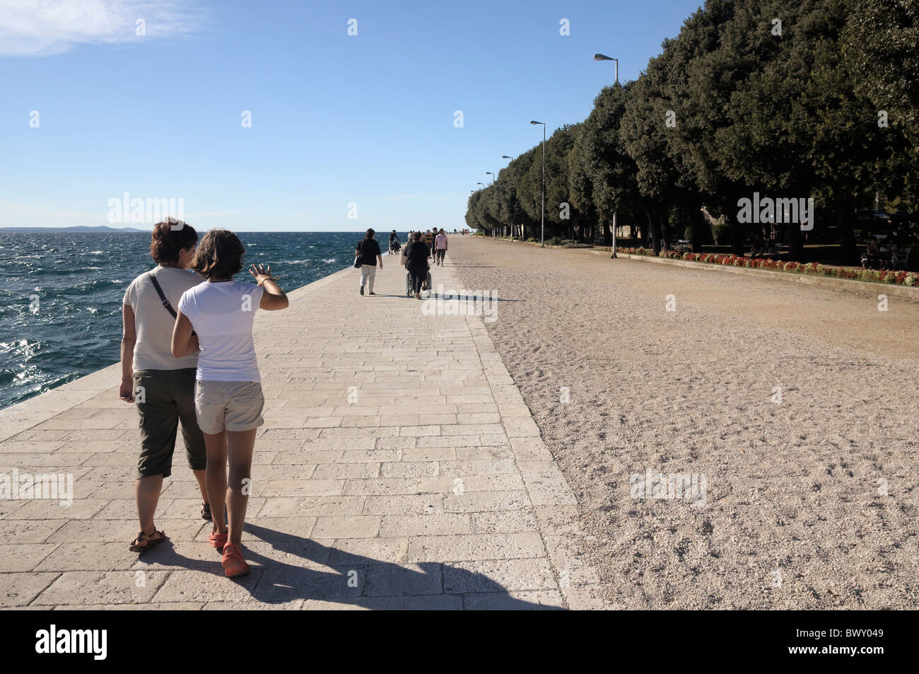 Menschen zu Fuß entlang der Ufermauer Uferpromenade Nova Riva Küste während der windigen Sommertagen, Zadar, Kroatien Stockfoto