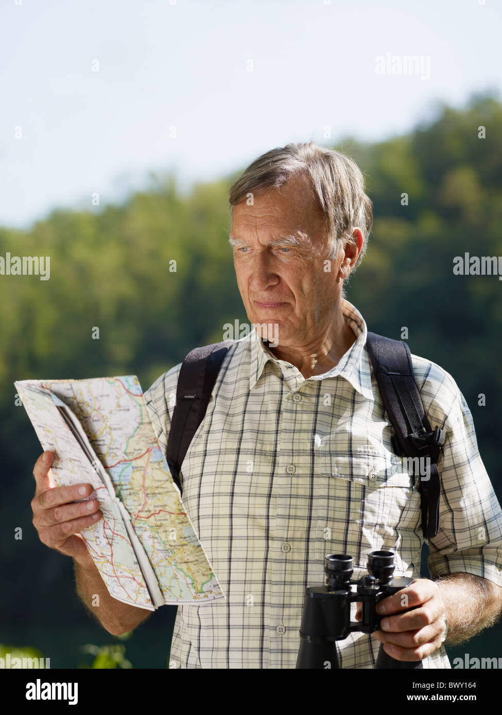 Senior Wanderer mit Karte und Fernglas. Textfreiraum Stockfoto