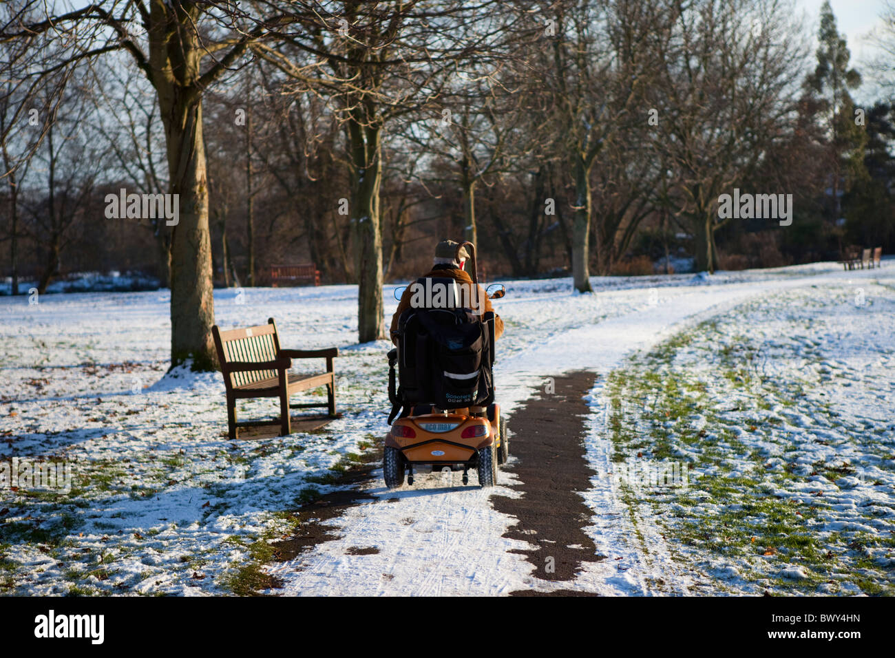 Person in eine elektrische Behinderung Rollstuhl/Buggy Fahrt durch Schnee bedeckt Park Bakewell Derbyshire East Midlands England Stockfoto