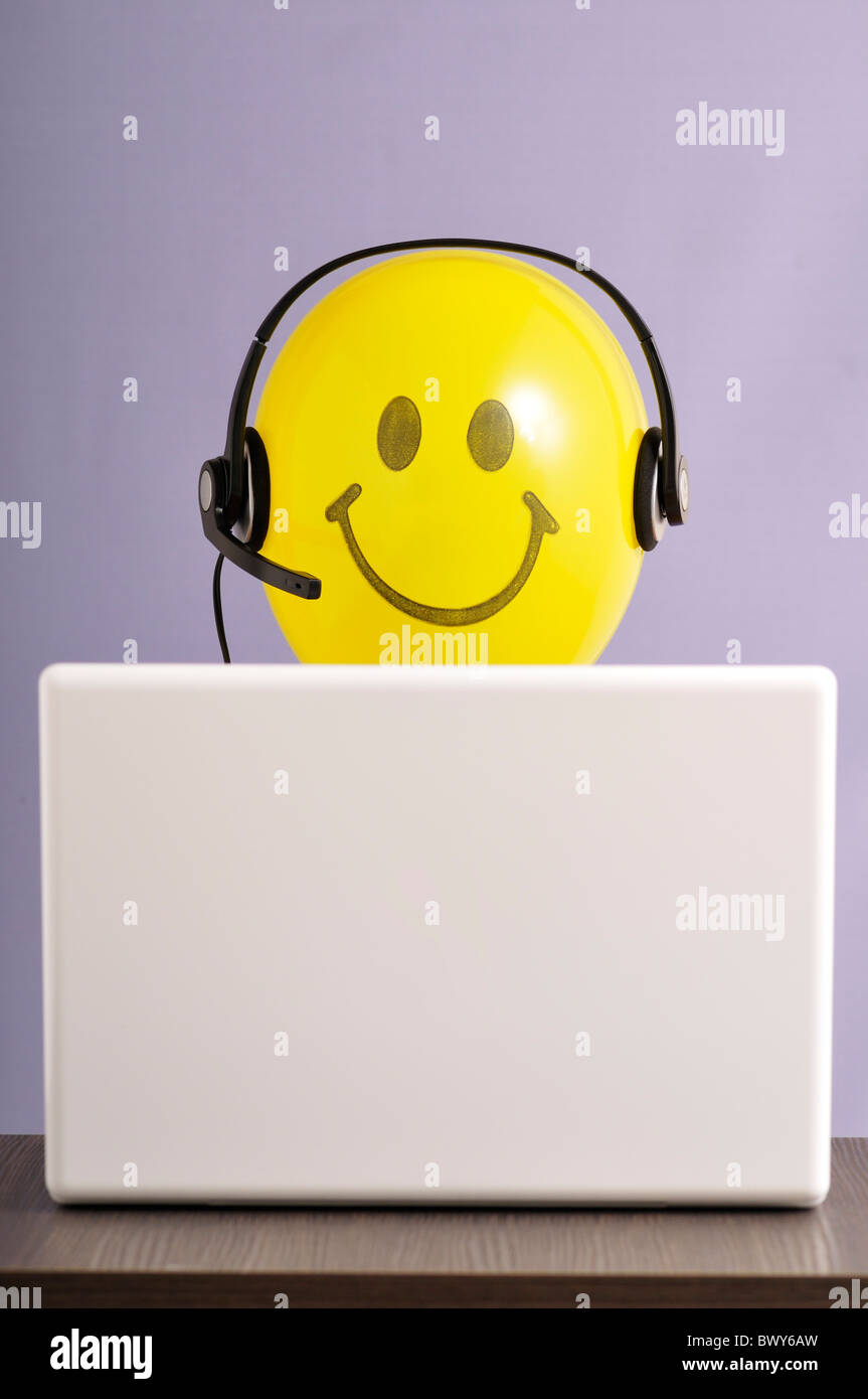 Smiley-Gesicht-Ballon mit Kopfhörer am Laptop-Computer Stockfoto
