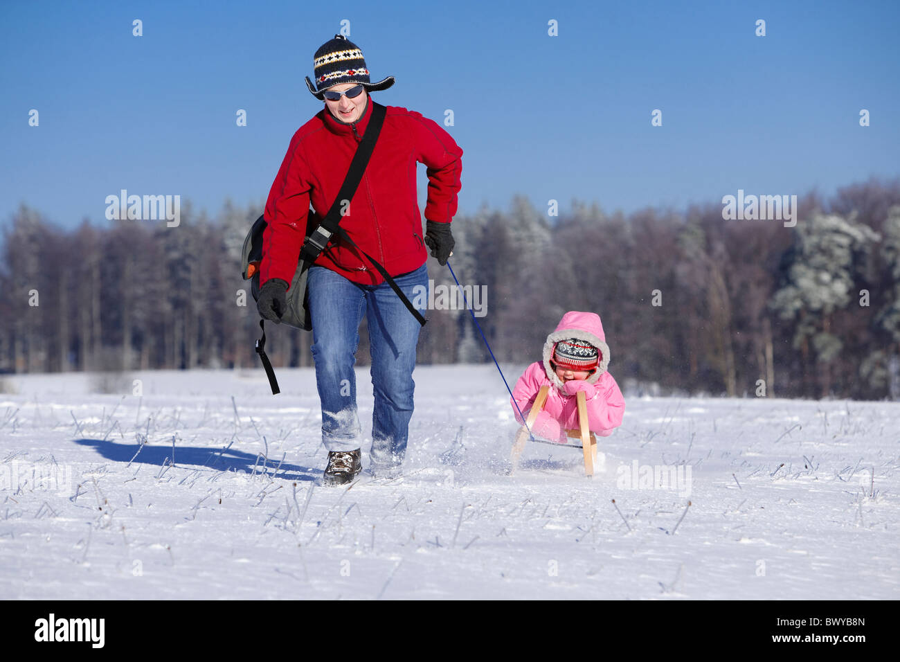 Frau Kleinkind Mädchen auf Holzschlitten in Winterlandschaft, Dobel, Schwarzwald, Gerrmany ziehen Stockfoto