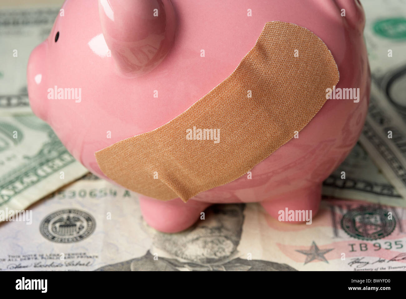 Heftpflaster auf rosa Sparschwein auf uns Dollar-Banknoten Stockfoto