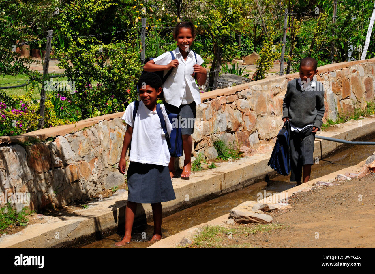 Drei Schülerinnen und Schüler spielt in den Wasser-Kanal. Prince Albert, Südafrika. Stockfoto