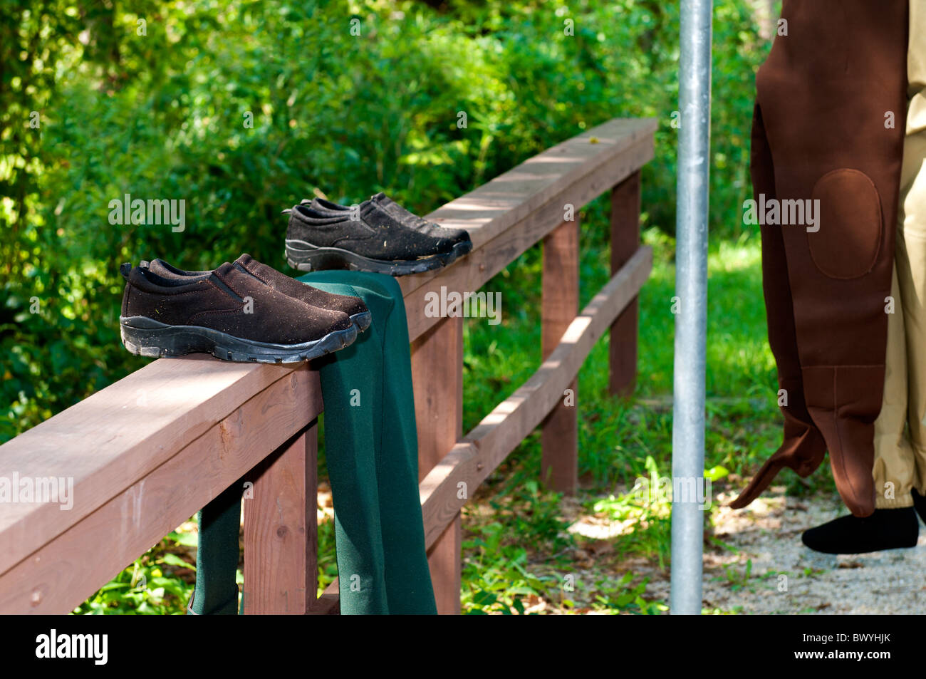 Waten, Schuhe und ein paar Stiefeln trocken auf einem hölzernen Zaun während zwei Paare von waders hängen von einer Stange in der Nähe auf einem Campingplatz. USA Stockfoto